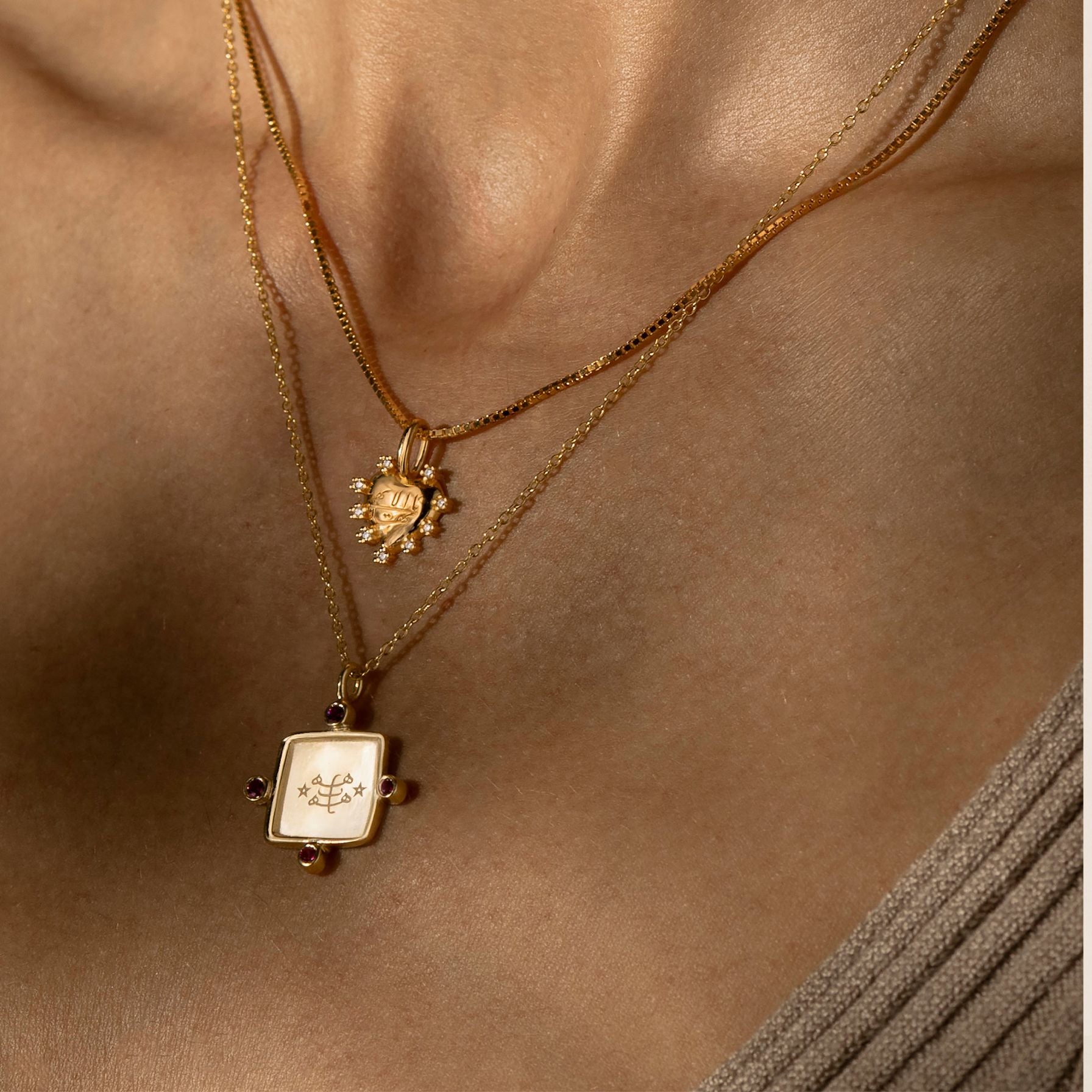 Two gold bahai necklaces with pendants on a person's neck