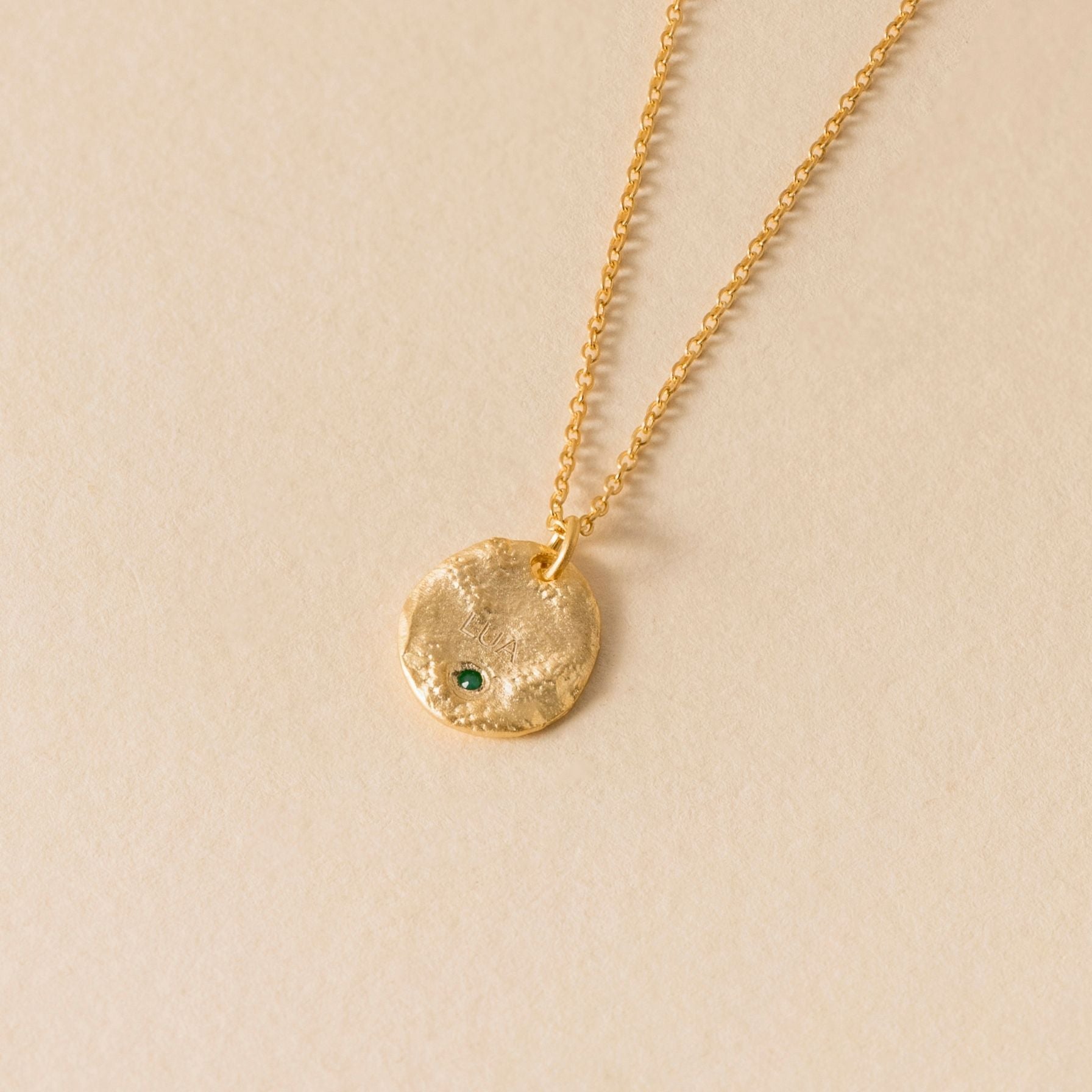 Gold lua nine pointed star necklace with an oval pendant on a beige background