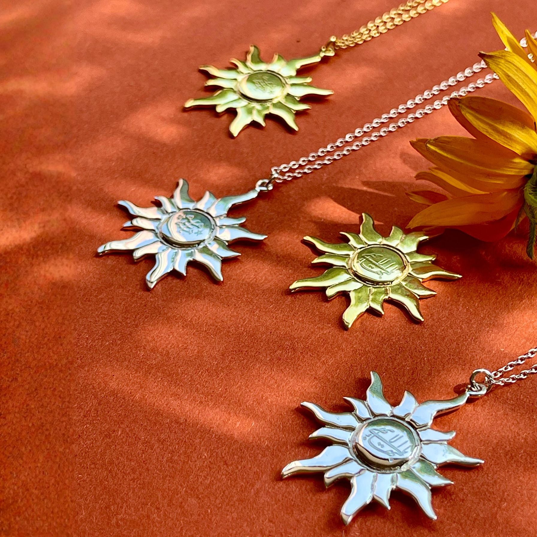 Sun-shaped pendants on chains with a sunflower on an orange fabric background
