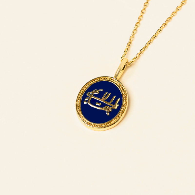 Gold pendant necklace with a bespoke enamel center featuring the greatest name symbol, on a light beige background.