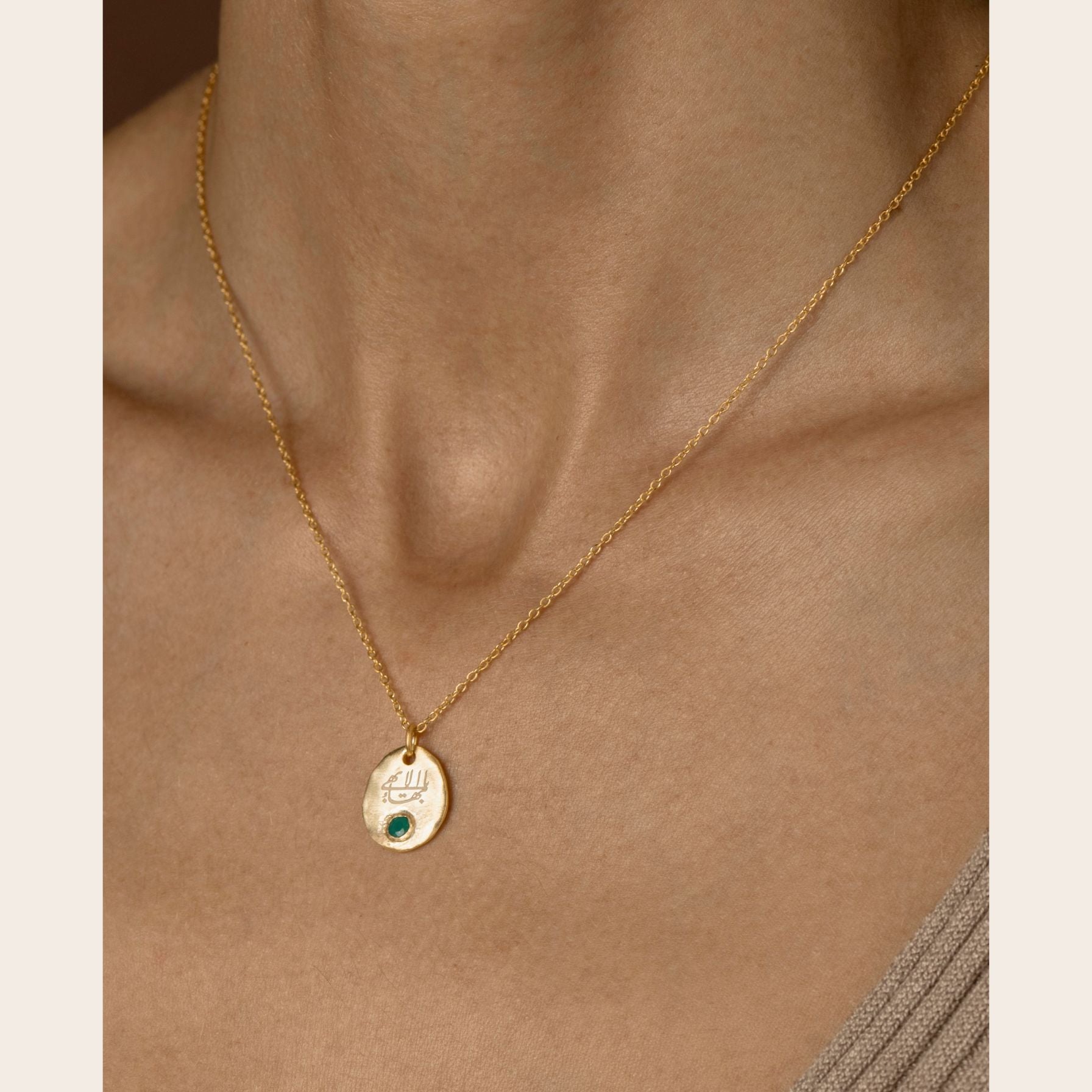 Gold necklace with a greatest name pendant on a person's neck