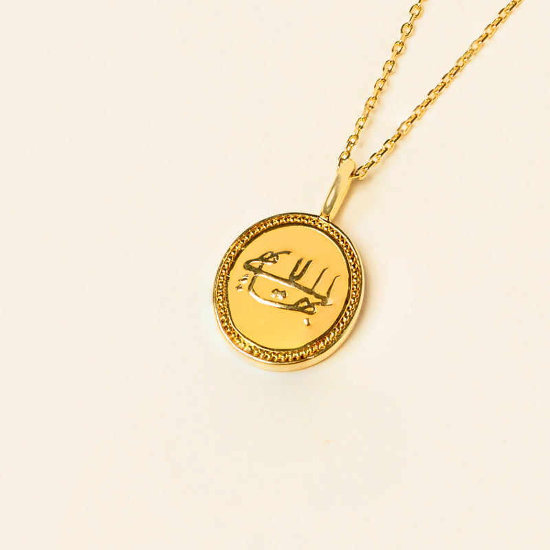Gold pendant necklace with a minimalist greatest name design, displayed on a plain beige background.
