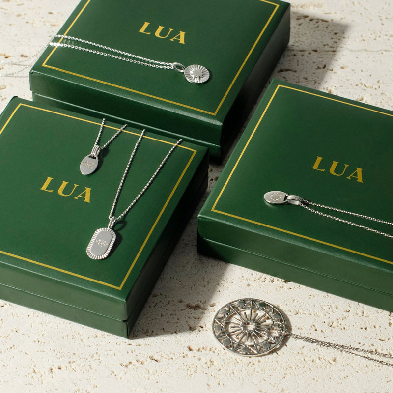 Three green boxes with yellow trim and the word "LUA" printed on them, arranged in a row on a beige textured surface, evoke a timeless style.