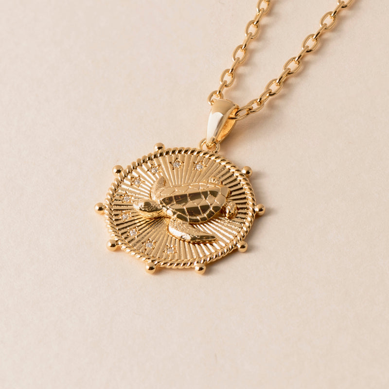 Introducing the Patience Turtle Necklace, a stunning gold pendant featuring a turtle design on a textured circular background, symbolizing patience and perseverance.