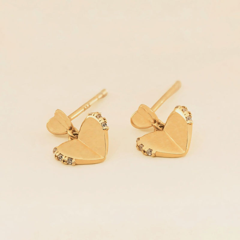 A pair of gold heart-shaped stud earrings with small inset stones along the edges, embodying the timeless style and virtue of love.