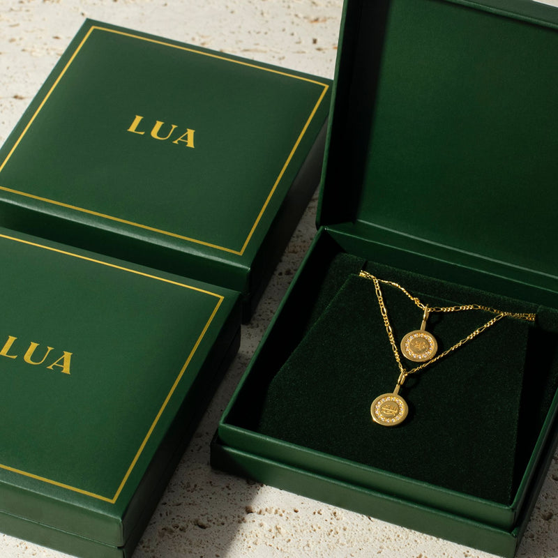 Three green boxes with yellow trim and the word "LUA" printed on them, arranged in a row on a beige textured surface, evoke a timeless style.