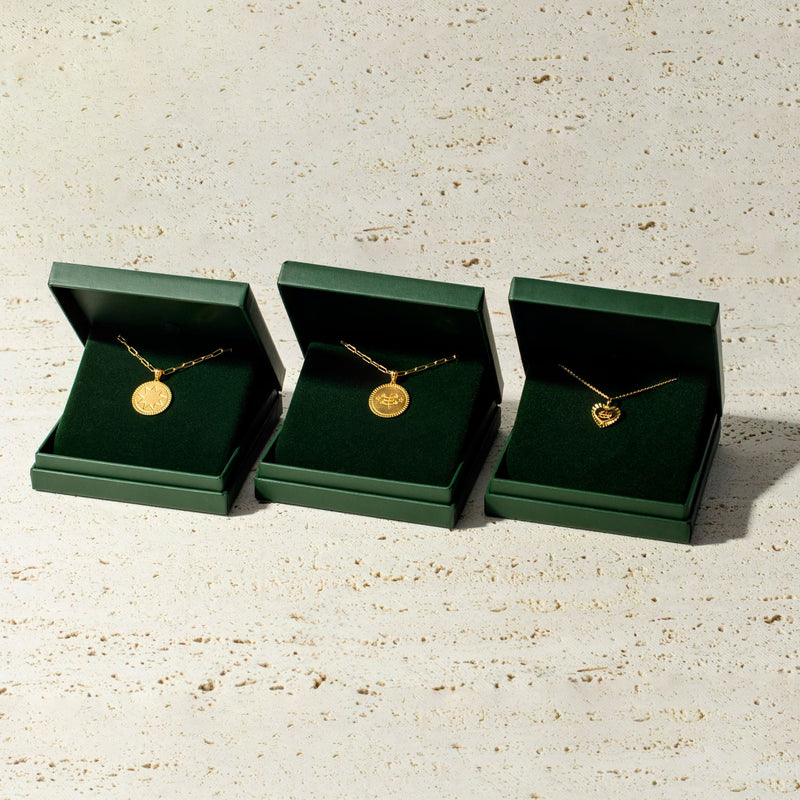 Three green boxes with yellow trim and the word "LUA" printed on them, arranged in a row on a beige textured surface, evoke a timeless style.