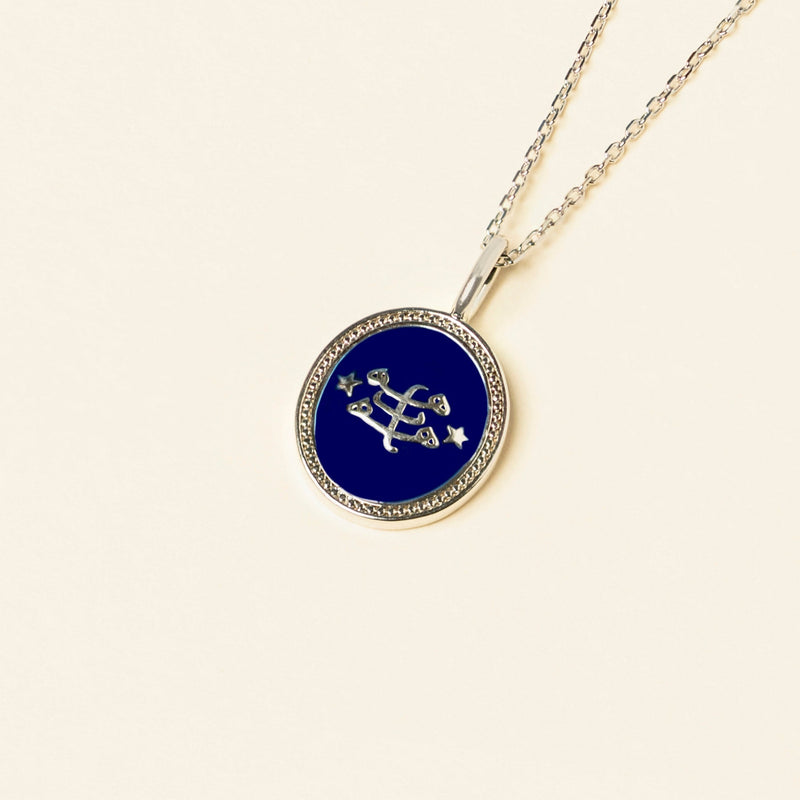 A pendant with a blue enamel center featuring a silver Ringstone Symbol, surrounded by small Nine-Pointed Star accents, on a silver chain against a light background.